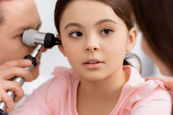 Foyer sélectif du médecin ent examinant l'oreille de la jeune fille mignonne avec otoscope — Photo de stock