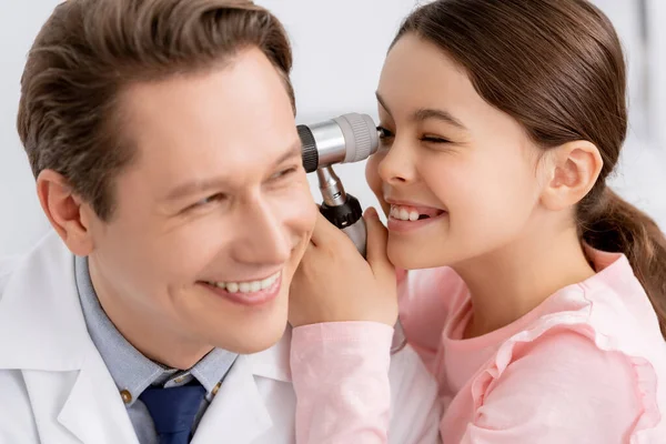 Criança alegre examinando orelha de médico ent com otoscópio — Fotografia de Stock