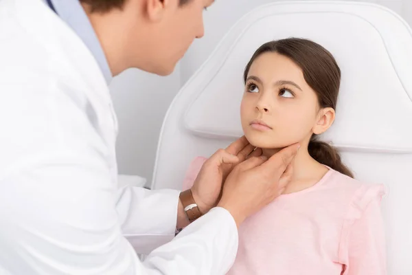Teilansicht eines lächelnden HNO-Arztes, der Hals eines süßen Kindes berührt, während er ihre Kehle untersucht — Stockfoto