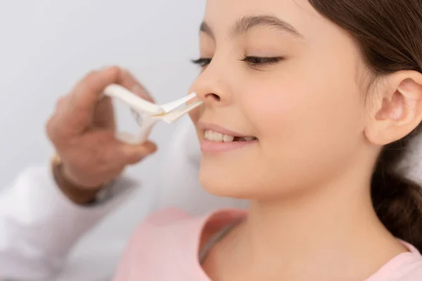 Vue recadrée du médecin ent examinant le nez d'un enfant souriant avec spéculum nasal — Photo de stock