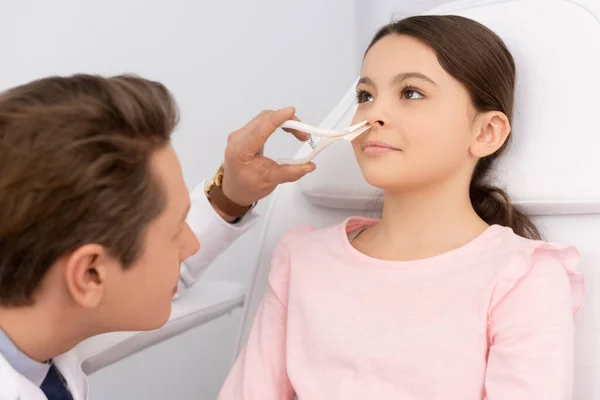 Médecin examinant le nez d'un enfant adorable avec spéculum nasal — Photo de stock