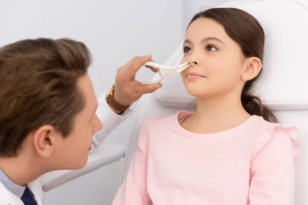 Ent physician examining nose of adorable child with nasal speculum — Stock Photo