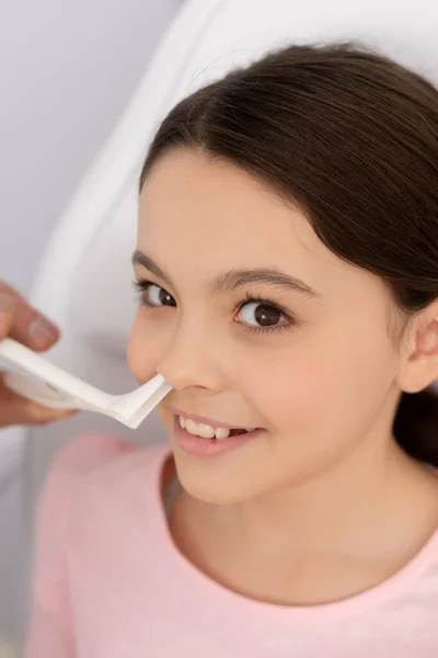 Partial view of ent physician examining nose of smiling kid with nasal speculum — Stock Photo