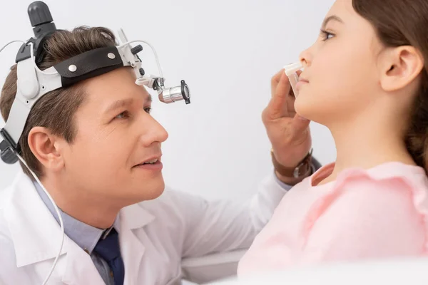 Enfoque selectivo de médico atento ent examinar la nariz de un niño lindo con espéculo nasal - foto de stock