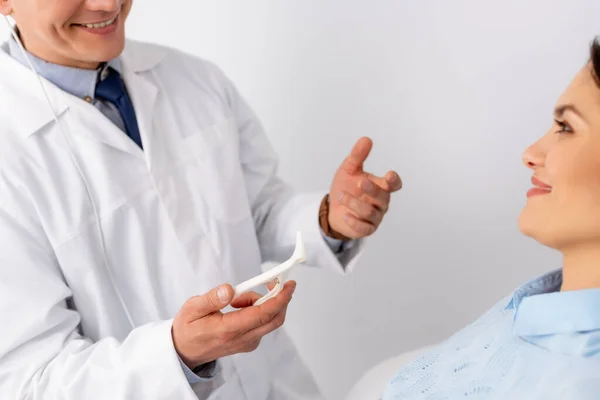 Cropped view of smiling ent physician holding nasal speculum near attractive patient — Stock Photo