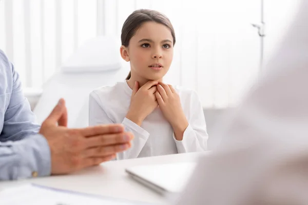 Selektiver Fokus des Kindes, das den Hals berührt, während es in der Nähe des Vaters sitzt, auf Konsultation mit dem Hals-Nasen-Ohren-Arzt — Stockfoto