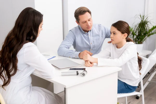Padre attento seduto vicino a figlia preoccupata durante la consultazione con il medico ent — Foto stock
