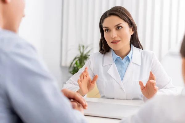 Selective focus of attractive ent physician talking to patients — Stock Photo