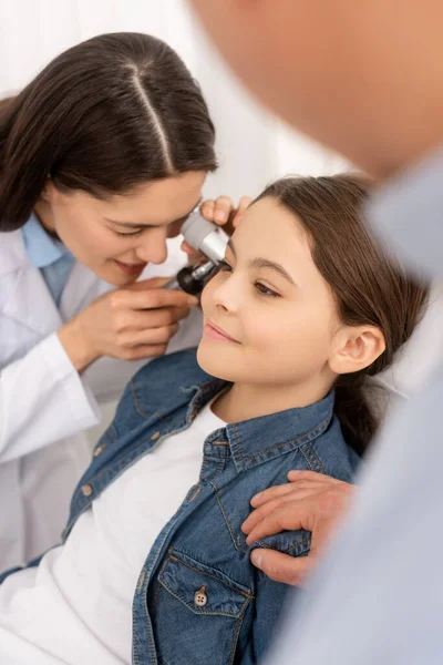 Abgeschnittene Ansicht des Vaters, der die Schulter seiner Tochter berührt, während der HNO-Arzt ihr Ohr mit Otoskop untersucht — Stockfoto