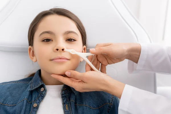 Cropped view of otolaryngologist examining nose of kid with nasal speculum — Stock Photo