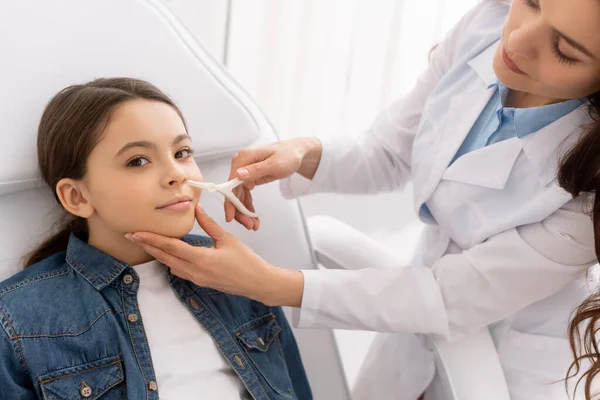 Attentive ent physician examining nose of kid with nasal speculum — Stock Photo