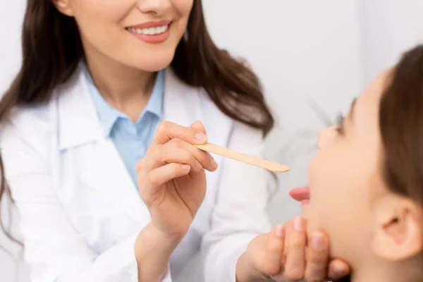 Vue recadrée du médecin ent examiner la gorge de l'enfant avec un dépresseur de la langue — Photo de stock