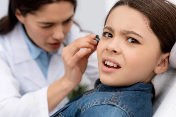Селективний фокус уважного отоларинголога, який вивчає вухо наляканої дитини — стокове фото