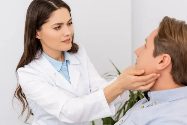 Médico hermoso, atento ent examinando paciente en clínica - foto de stock