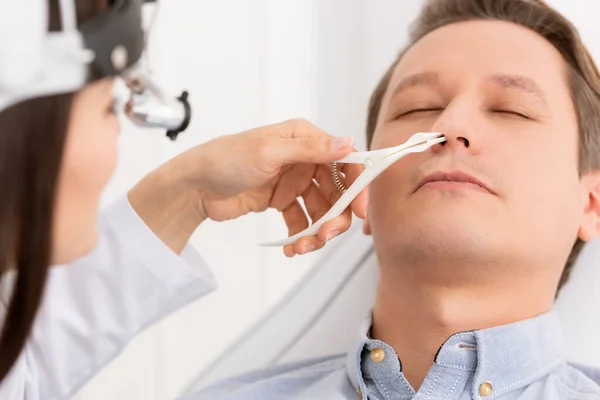 Visão recortada de otorrinolaringologista examinando nariz de homem bonito com espéculo nasal — Fotografia de Stock