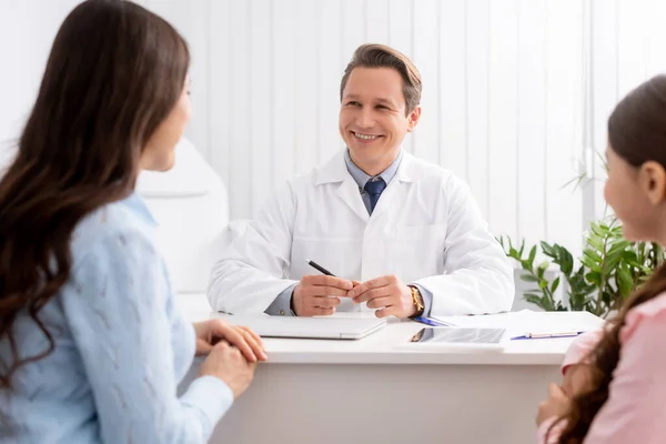 Smiling ent physician talking to mother and daughter during consultation — Stock Photo