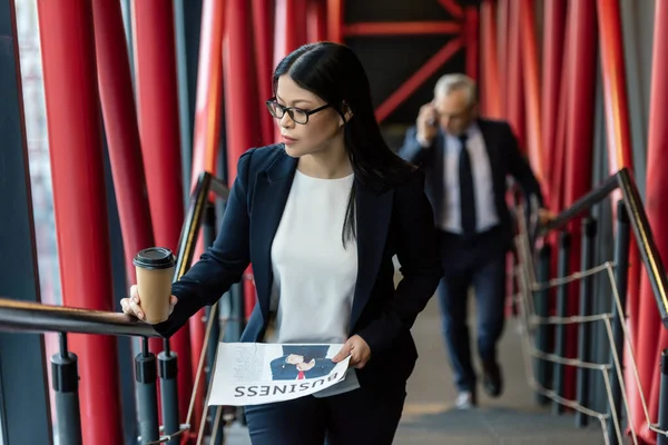 Asiatique femme d'affaires avec tasse en papier et journal entreprise regardant loin — Photo de stock