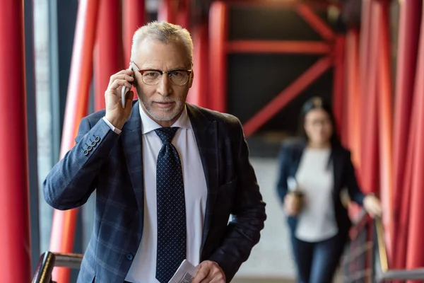 Geschäftsmann im Anzug spricht auf Smartphone und blickt in Kamera — Stockfoto