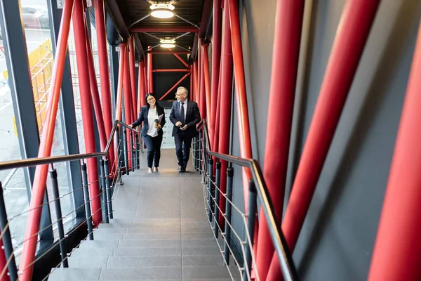 High angle view of smiling businessman and asian businesswoman walking on stairs — Stock Photo