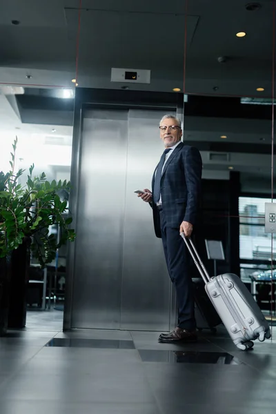 Visão de baixo ângulo de homem de negócios com saco de viagem de pé perto do elevador — Fotografia de Stock