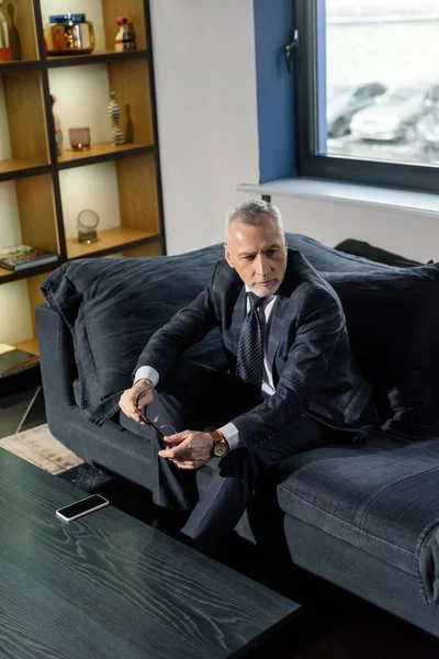 High angle view of businessman in suit sitting on sofa and holding glasses — Stock Photo