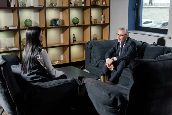 Бізнесмен і бізнес-леді в офіційному одязі розмовляють і сидять на дивані — стокове фото