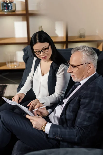 Geschäftsmann und lächelnde asiatische Geschäftsfrau, die redet und Papiere hält — Stockfoto