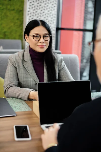 Selective focus of smiling asian businesswoman talking with businessman in cafe — Stock Photo