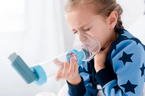 Sick kid with closed eyes using inhaler with spacer — Stock Photo