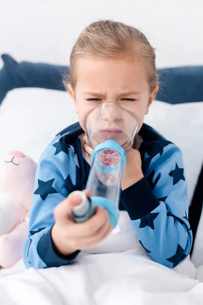 Messa a fuoco selettiva del bambino asmatico utilizzando l'inalatore con distanziatore — Foto stock