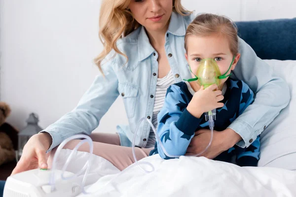 Caring mother near asthmatic daughter using compressor inhaler — Stock Photo