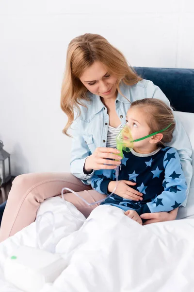 Mère attentionnée toucher masque respiratoire sur fille asthmatique en utilisant un inhalateur compresseur — Photo de stock