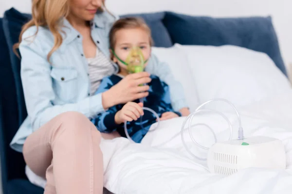 Selective focus of compressor inhaler near asthmatic kid and caring mother — Stock Photo