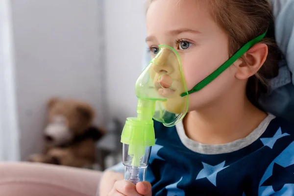 Niño enfermo usando máscara respiratoria en casa - foto de stock