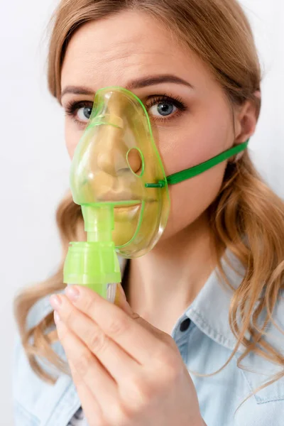 Mujer enferma sosteniendo máscara respiratoria cerca de la cara - foto de stock