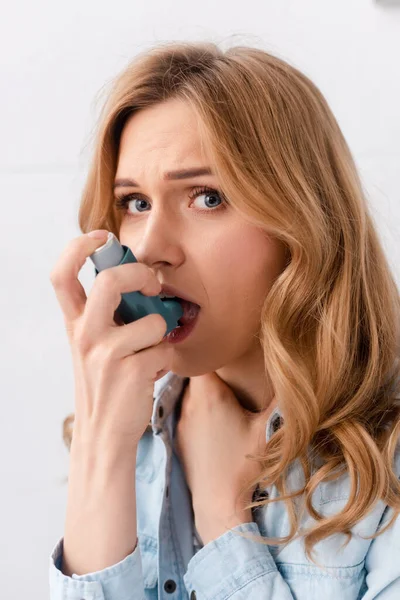 Beautiful and asthmatic woman using inhaler and looking at camera — Stock Photo