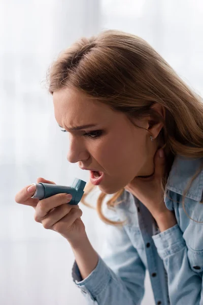Asthmatic woman holding inhaler and touching neck — Stock Photo