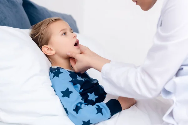 Doctor en bata blanca examinando niño enfermo - foto de stock