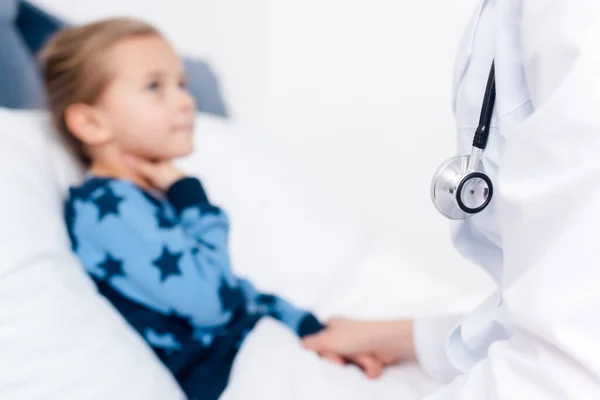 Foyer sélectif du médecin en manteau blanc près de l'enfant malade — Photo de stock