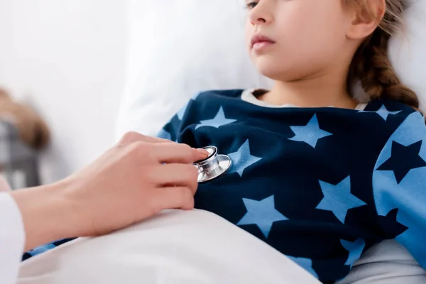 Vista recortada del médico con estetoscopio que examina al niño enfermo - foto de stock