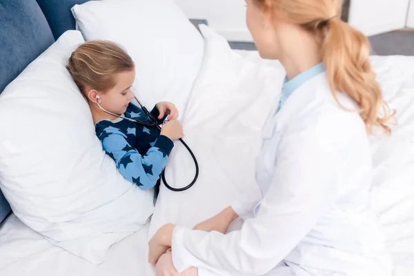 Selective focus of sick kid holding stethoscope near doctor — Stock Photo