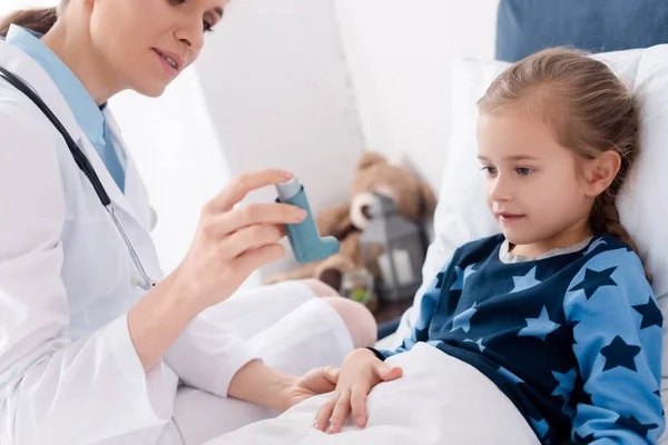 Arzt im weißen Kittel hält Inhalator in der Nähe von asthmatischem Kind — Stockfoto