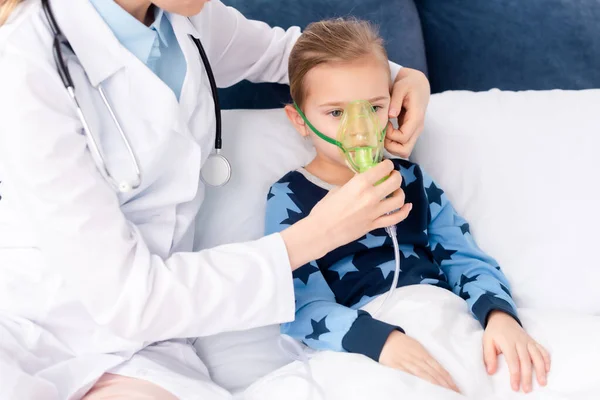 Doctor touching respiratory mask on asthmatic kid — Stock Photo