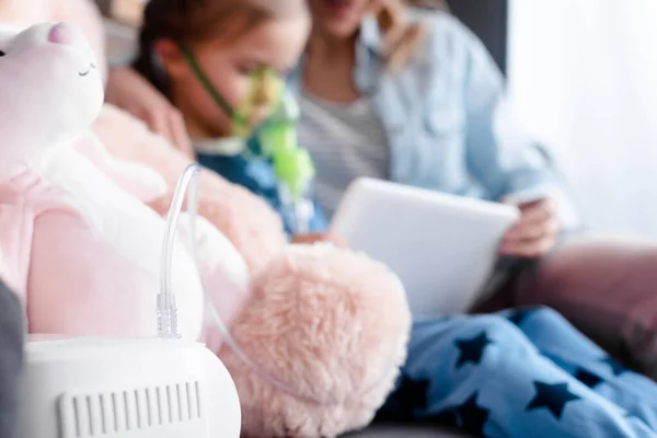 Selective focus of compressor inhaler near sick kid and mother using digital tablet — Stock Photo