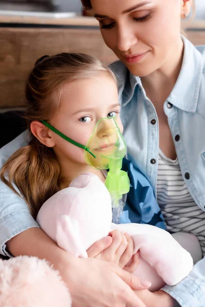 Asthmatic kid using respiratory mask near mother — Stock Photo