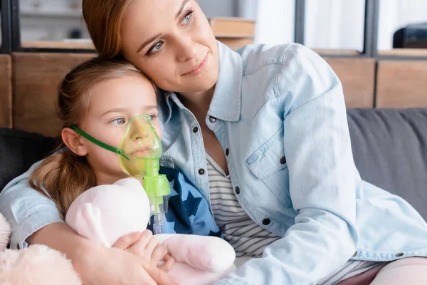 Madre che abbraccia figlia asmatica in maschera respiratoria — Foto stock