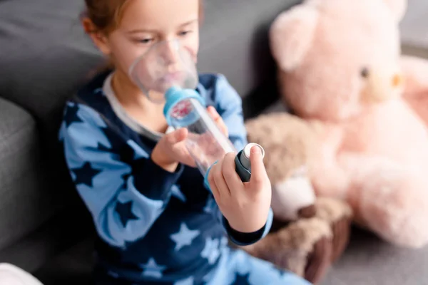 Foyer sélectif de l'enfant malade en utilisant un inhalateur avec espaceur près de jouets mous — Photo de stock