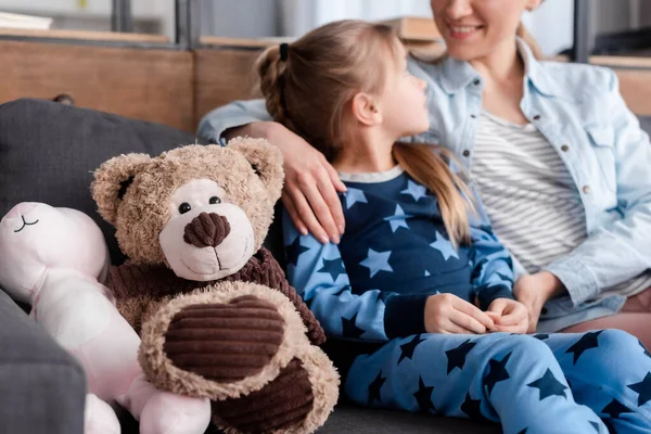 Enfoque selectivo de los juguetes blandos cerca del niño mirando a la madre feliz — Stock Photo