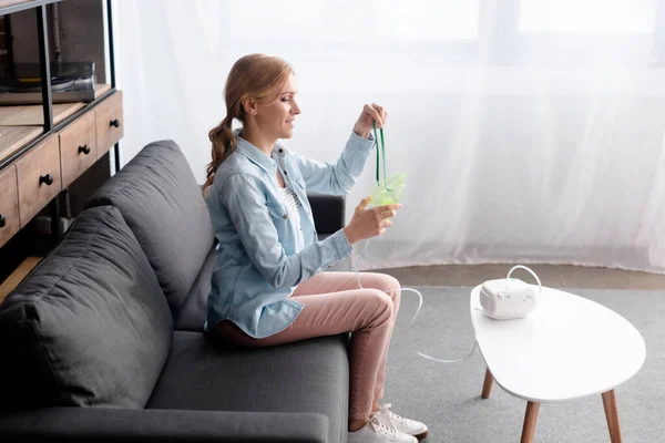 Side view of happy woman with asthma holding respiratory mask near compressor inhaler — Stock Photo