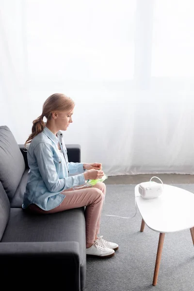 Vista lateral de la mujer con asma que sostiene la máscara respiratoria cerca del inhalador del compresor - foto de stock